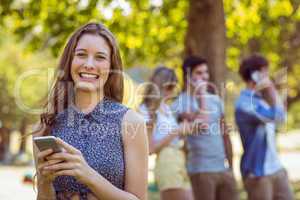 Happy friends in the park using their phones