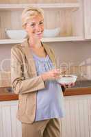 Blonde pregnancy smiling at camera and eating