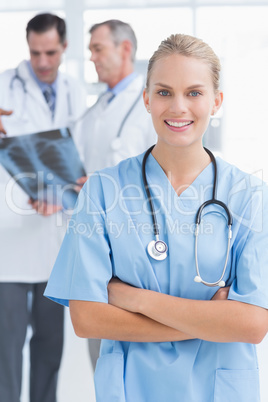 Smiling doctor looking at camera while her colleagues works