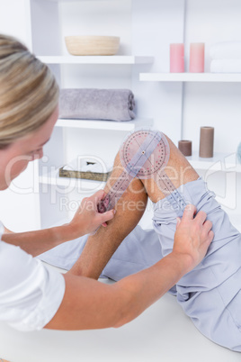 Doctor examining man leg with tool