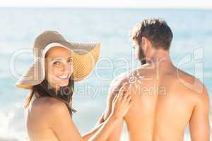 pretty brunette putting sun tan lotion on her boyfriend