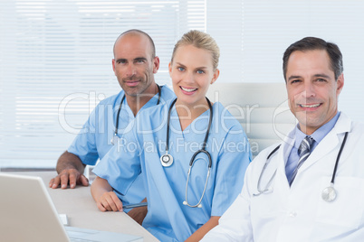 Smiling doctors looking at camera with his colleagues