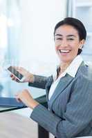 Smiling businesswoman using smartphone and tablet