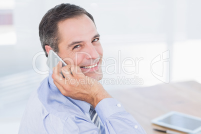 Smiling businessman phoning at his desk