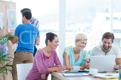 Creative colleagues using laptop in meeting