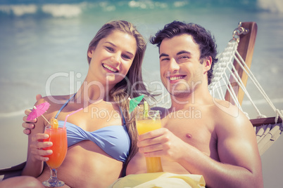 Cute couple in the hammock drinking a cocktail