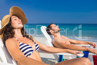 Happy couple relaxing on deck chair at the beach