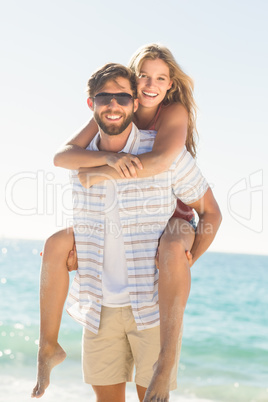Handsome man giving piggy back to his girlfriend