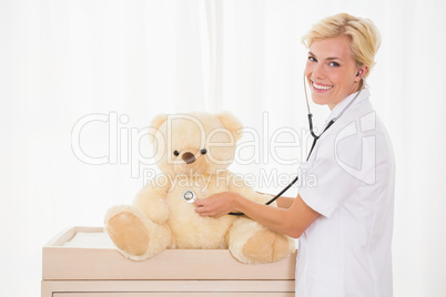 Portrait of a blonde doctor with stethoscope and teddy bear