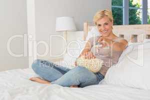 Portrait blonde woman watiching TV and eating pop corn