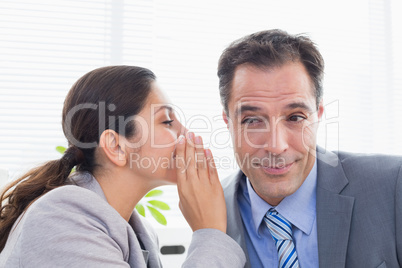 Businesswoman whispering something to her colleague