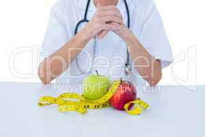 Doctor sitting behind his desk with green and red apples