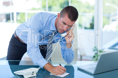 Businessman having a phone call and writing notes