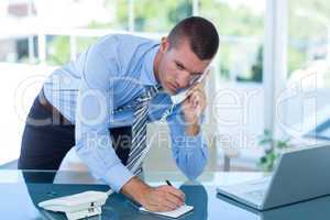 Businessman having a phone call and writing notes