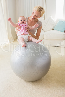 Happy mother with her baby girl in the exercice ball