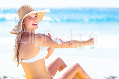 Pretty blonde woman spreading sun tan lotion on her arms