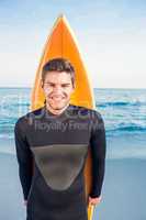 Man in wetsuit with a surfboard on a sunny day