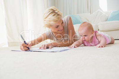 Smiling mother with her baby girl writting on a copybook