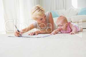 Smiling mother with her baby girl writting on a copybook