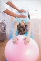 Trainer working with woman on exercise ball