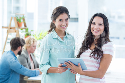 smiling businesswomen using a tablet with colleagues