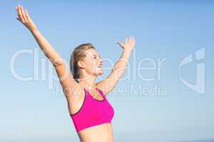 Wear view of beautiful fit woman cheering with arms rise