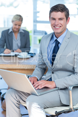 Smiling young businessman using his laptop