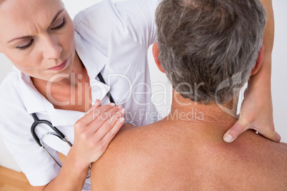 Doctor examining her patient shoulder