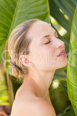 Beautiful blonde smiling at camera behind leaf