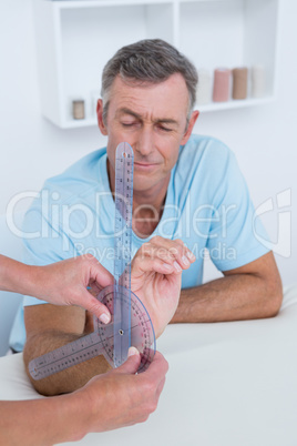 Doctor measuring wrist with goniometer