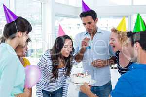 Businesswoman blowing candles on her birthday cake
