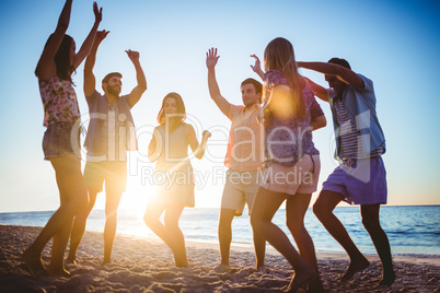 Happy friends dancing on the sand