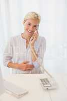Portrait smiling blonde woman using computer and phoning