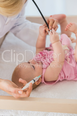 Beautiful baby girl and doctor using syringue and needle