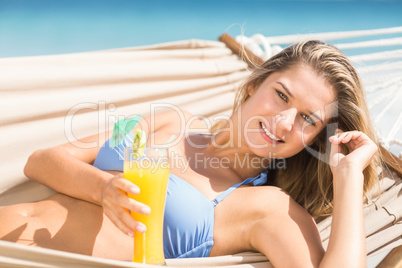 Pretty woman holding cocktail in the hammock