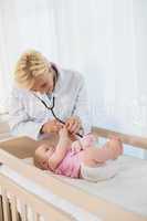 Happy blonde doctor and baby girl using stethoscope
