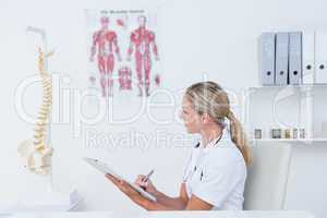 Doctor writing on clipboard at her desk