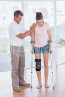 Doctor helping his patient walking with crutch