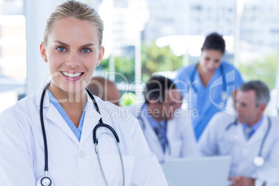 Smiling female doctor looking at camera while her colleagues wor
