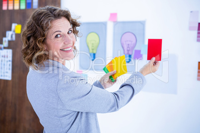 Creative businesswoman holding color cards and looking at camera