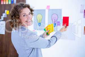 Creative businesswoman holding color cards and looking at camera
