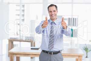 Businessman smiling at camera with thumbs up