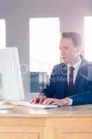 Serious businessman typing on computer