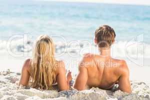 Happy couple relaxing together in the sand