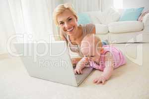 Happy blonde mother with her baby girl using laptop