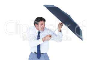 Businessman holding umbrella to protect himself