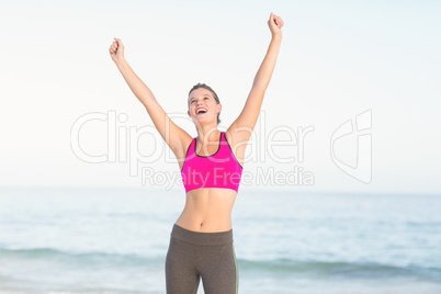 Wear view of beautiful fit woman cheering with arms rise