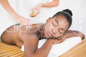 Masseuse pouring massage oil on a pretty woman back