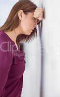 Depressed woman leaning her head against a wall