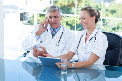 Smiling doctors working together on tablet